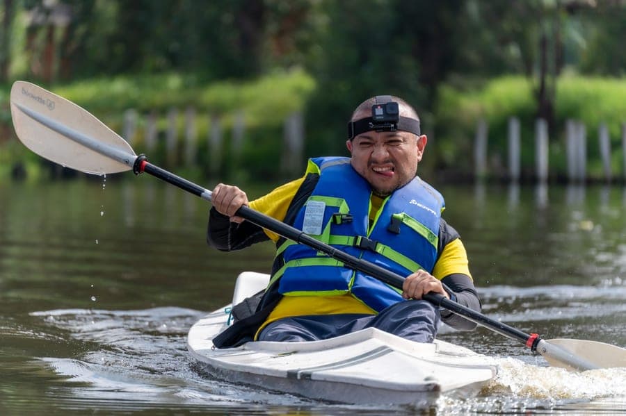 A paddler wearing a buckled life vest sitting in a kayak on open water
