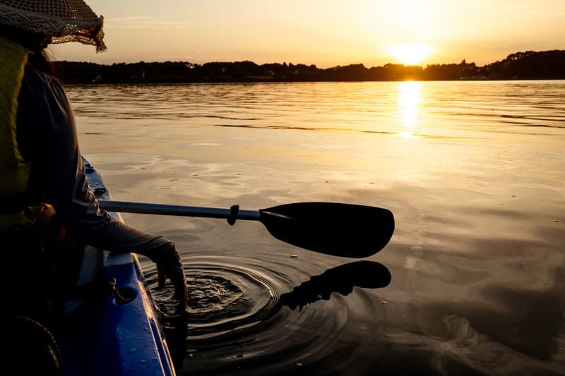 A kayak paddle resting across the deck of a boat